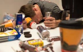 man passed out holding energy drink